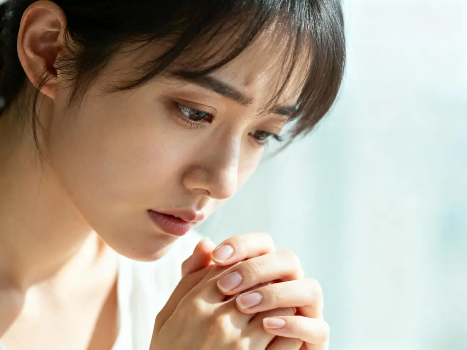 A thoughtful woman contemplating her habit of nail-biting, highlighting concerns about health risks.