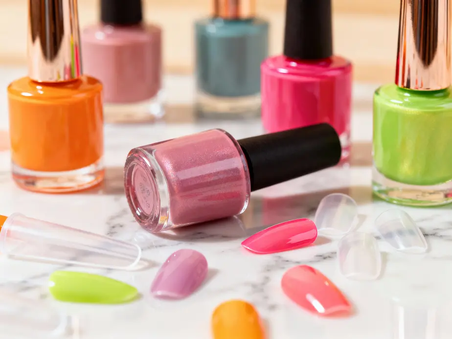 A vibrant display of nail care products including colorful polishes and acrylics on a marble surface.